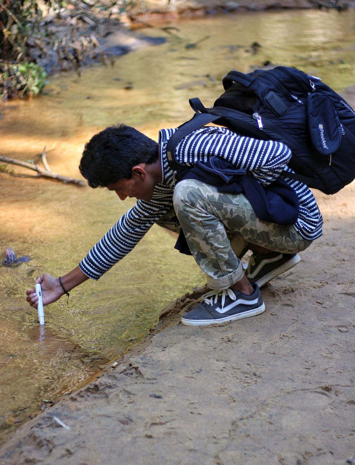 A researcher drawing a water sample into a bottle over the side of a boat